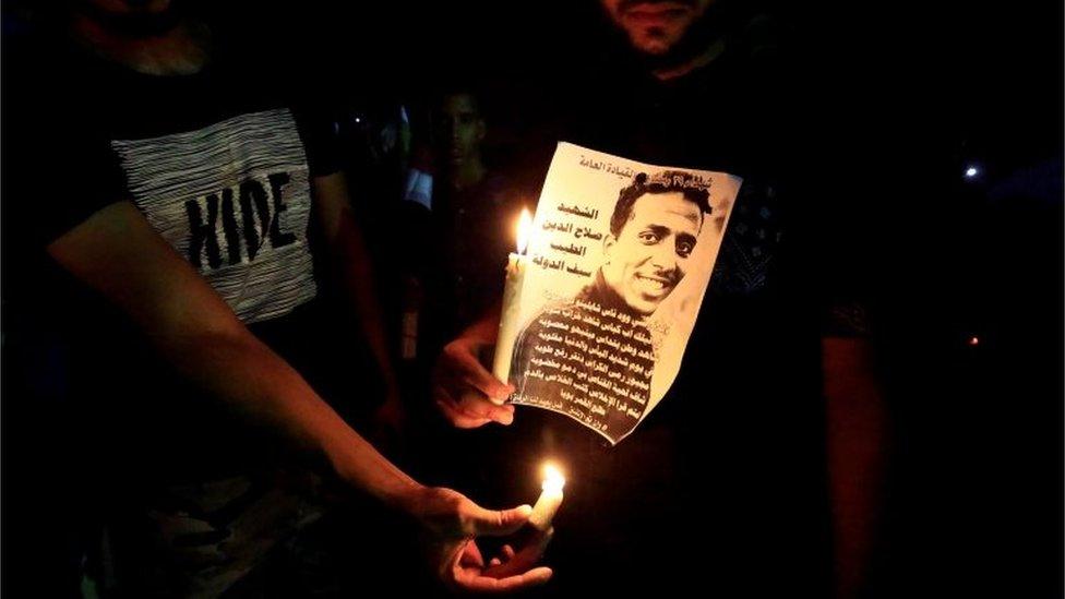 Sudanese protesters hold candles near a portrait of a civilian killed in march during a demonstration to commemorate 40 days since the sit-in massacre in Khartoum North, Sudan July 13, 2019