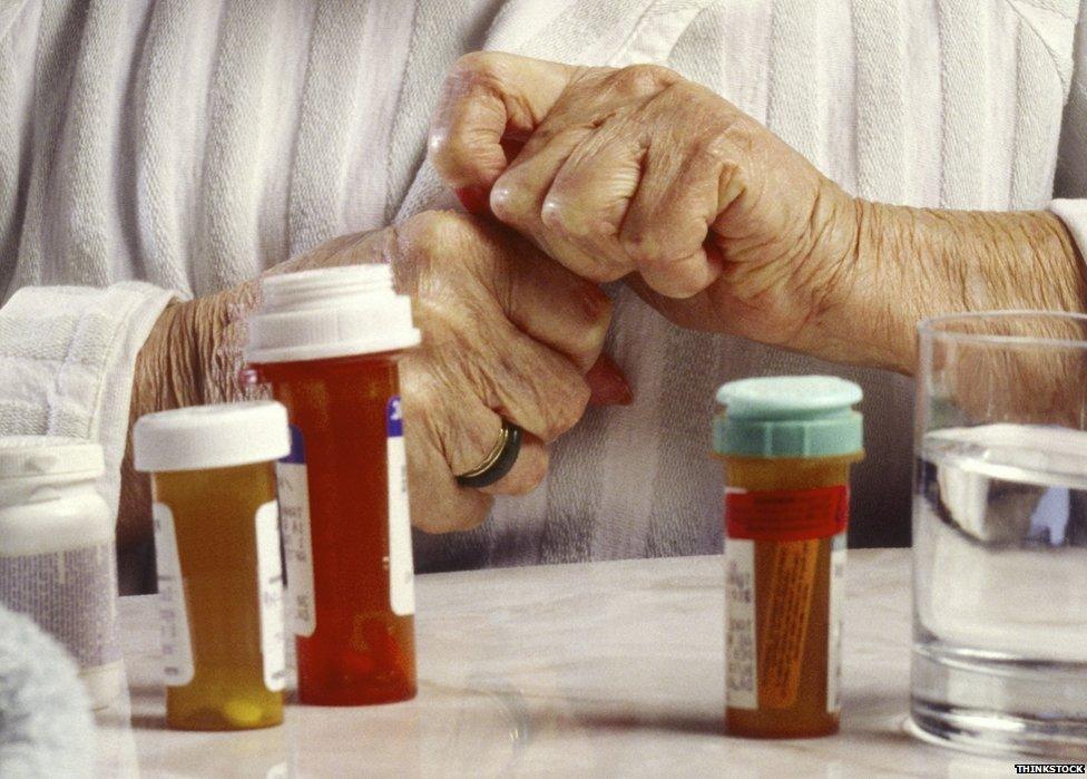 An elderly person opening a bottle of pills