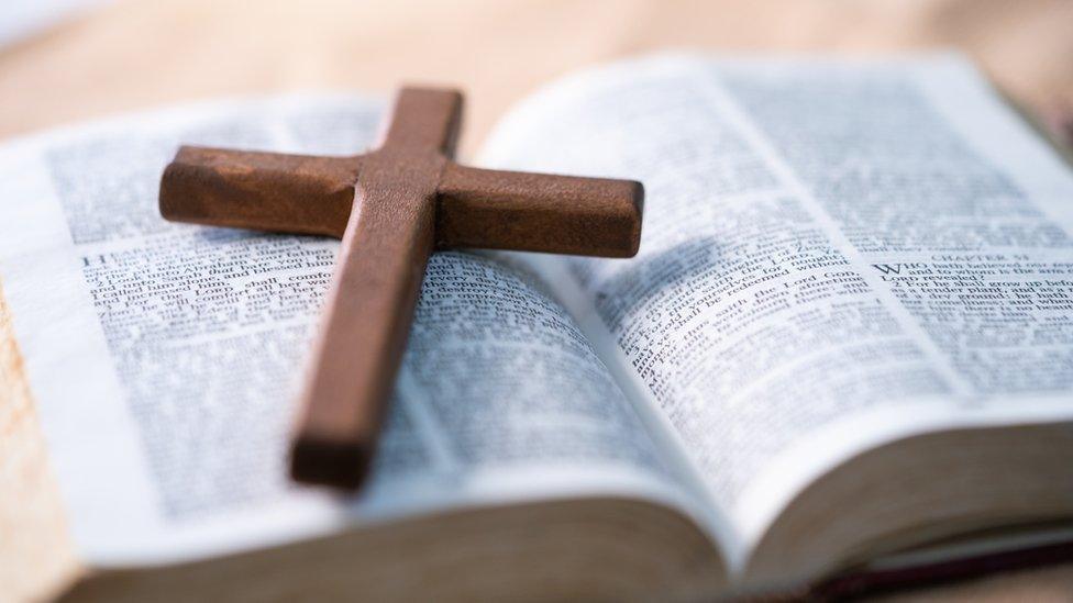 Wooden cross sits on top of open bible