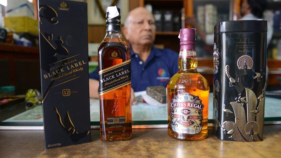 P.R.Man Singh poses beside bottles of imported alcohol at his store in Secunderabad, the twin city of Hyderabad on August 28, 2013.