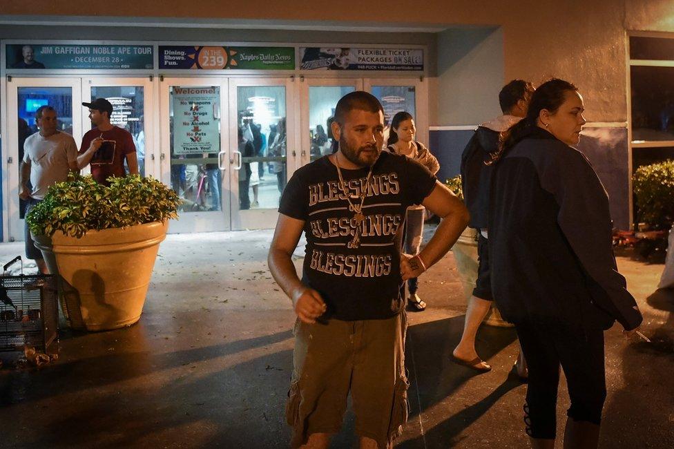 People smoke cigarettes outside the Germain Arena, a facility used to shelter local residents during hurricane Irma in Estero, Florida, 10 September