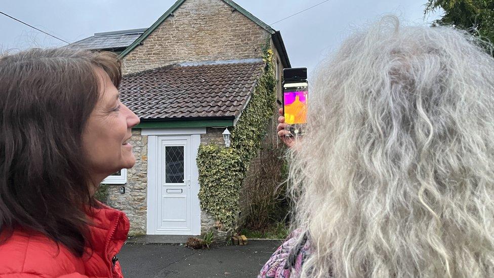 Two women looking at thermal images of a home, on a mobile phone