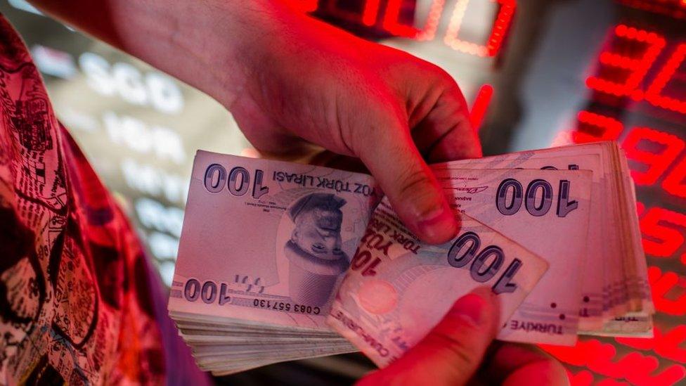 A money changer counts Turkish lira banknotes at a currency exchange office in Istanbul