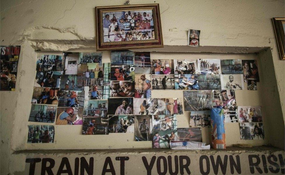 This picture taken on March 2, 2016, shows boxing memorabilia and photographs of past and current fighters plastered on a wall at Boxing trainer George Khosi"s Hillbrow boxing club on March 2, 2016, in Johannesburg. The Hillbrow boxing club used to be a petrol station before being turned into a boxing gym in the dilapidated neighbourhood of Hillbrow