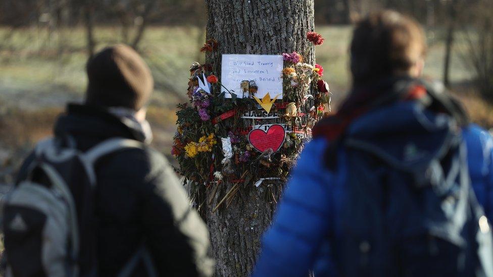 Passers-by stop to look at flowers and messages left by mourners in Freiburg