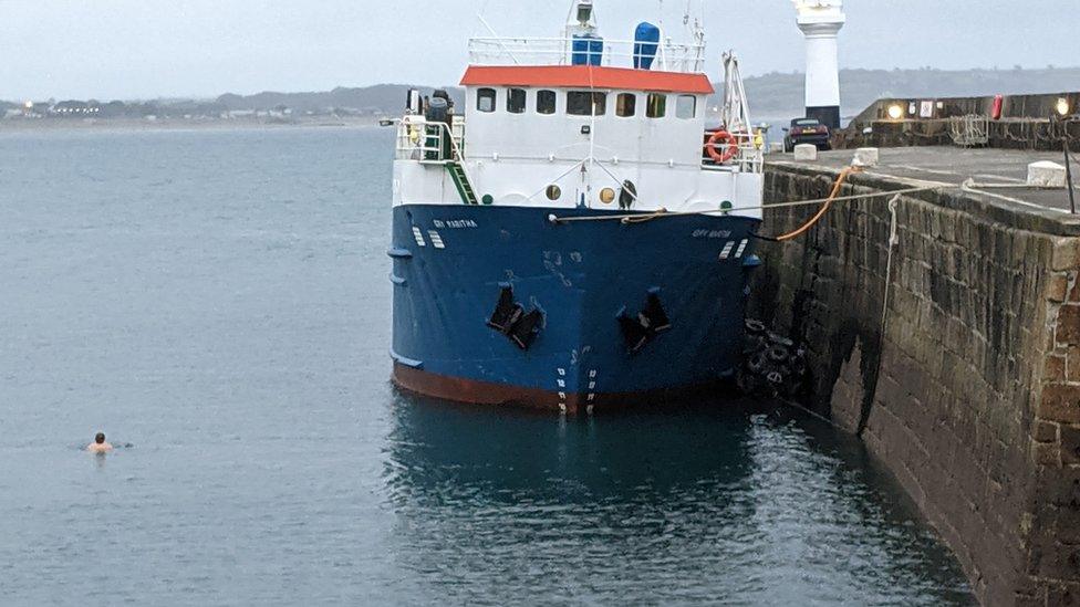 Swimmer in harbour near large boat