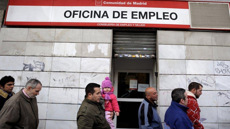 People wait in line to enter a government job centre in Madrid