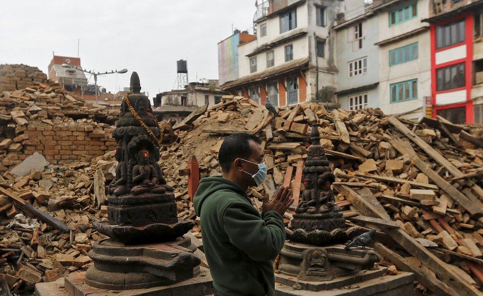 A man prays next to the rubble of a temple, destroyed in the April 2015 earthquake in Kathmandu