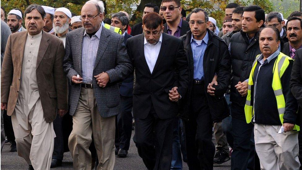 Dr Abdul Shakoor walks immediately behind the funeral cortege with a large group of people, as it arrives at Parndon Wood Cemetery, in Harlow, for his family's burial following their funeral service at Harlow Islamic Centre