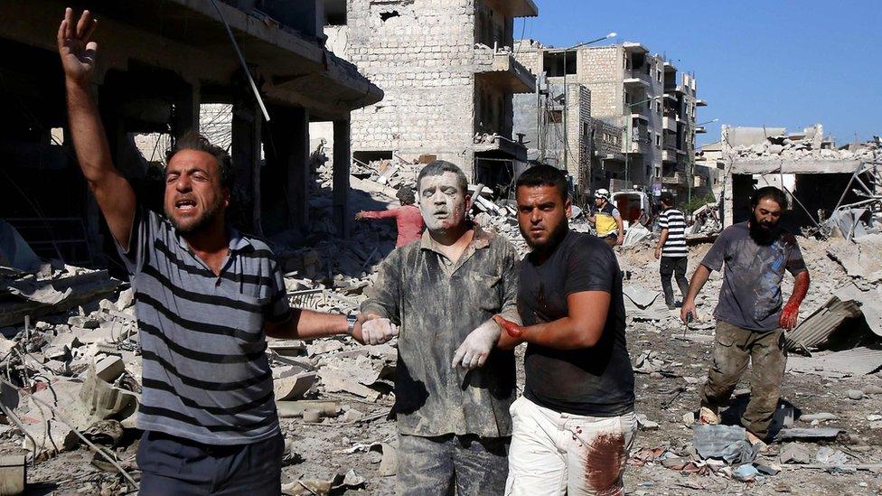 An injured man is led away after an after an air strike on a market place in the opposition-held town of Maarat al-Numan, Syria (22 July 2019)