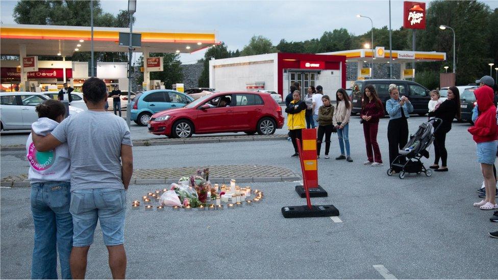 People lay candles and flowers at the site where a twelve year old girl was shot near a petrol station in Botkyrka, south of Stockholm, Sweden, 03 August 2020.