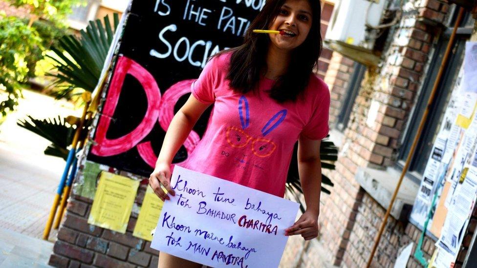 A woman holds a #HappyToBleed poster