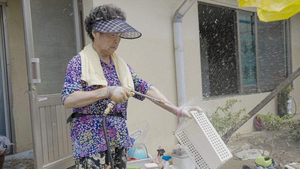 Han Chang Rae washes her mud-caked belongings with water in Eham, a tiny fishing village in South Korea