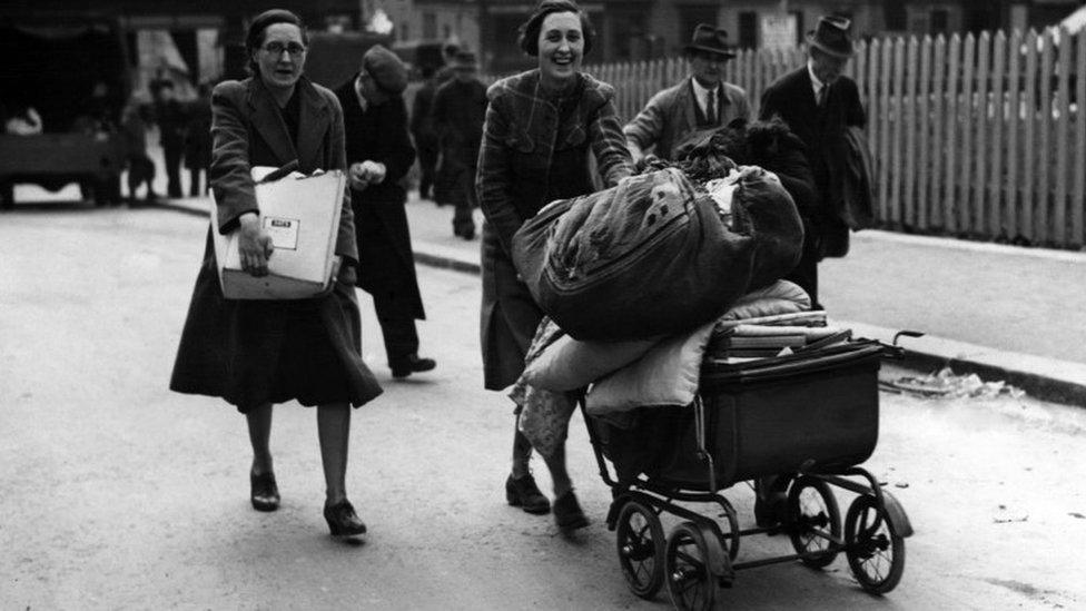 Women transporting their possessions in a pram after bombing raids damaged their home, Bath,1942