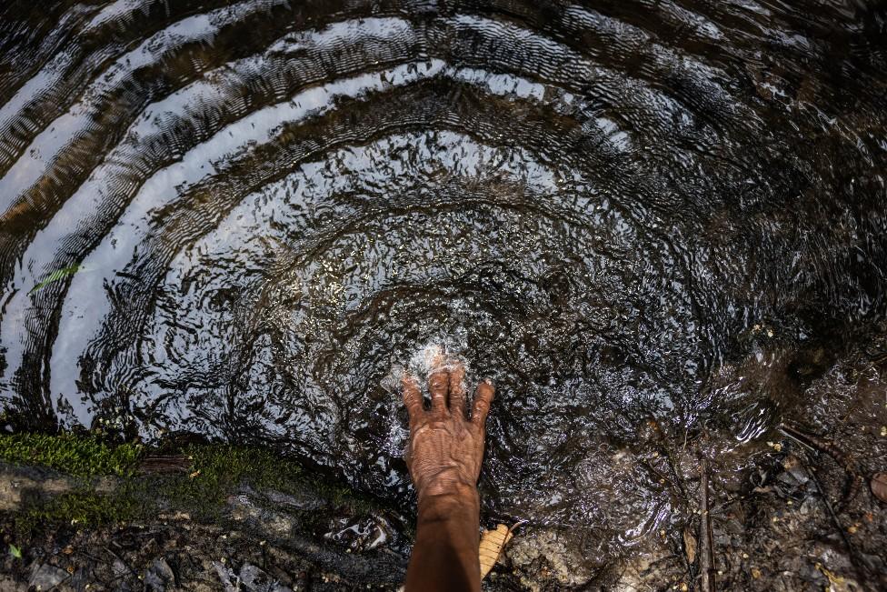 A woman puts her hand in the river