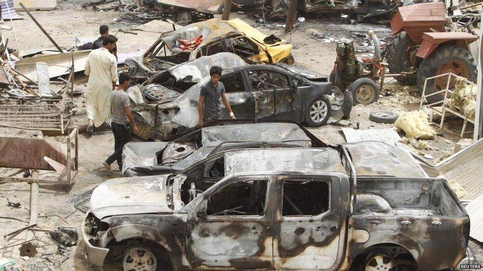 Residents look at the site of Friday's suicide car attack at a market in Khan Bani Saad, north-east of Baghdad (18 July 2015)