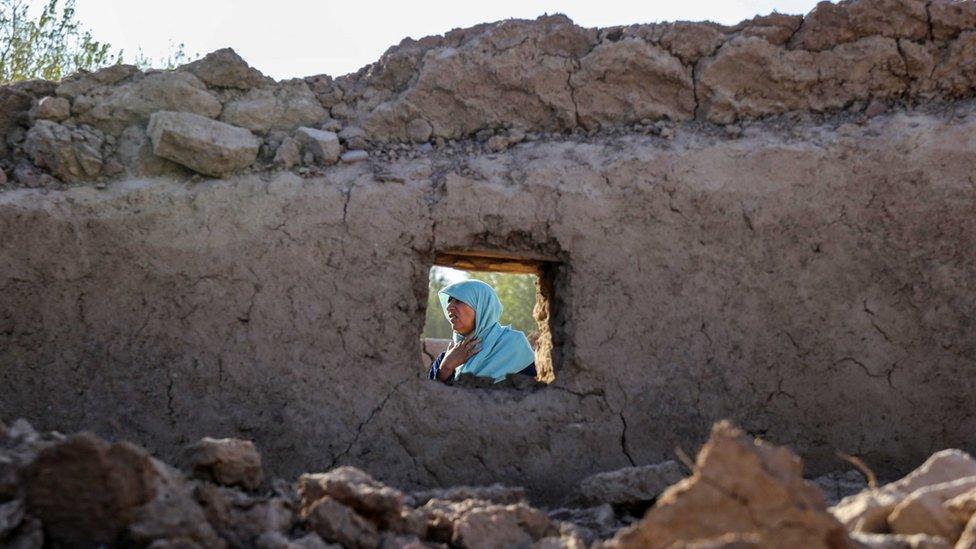 A woman sits behind the rubble of a building after earthquake earlier this week in Herat province, Afghanistan. Photo: 12 October 2023