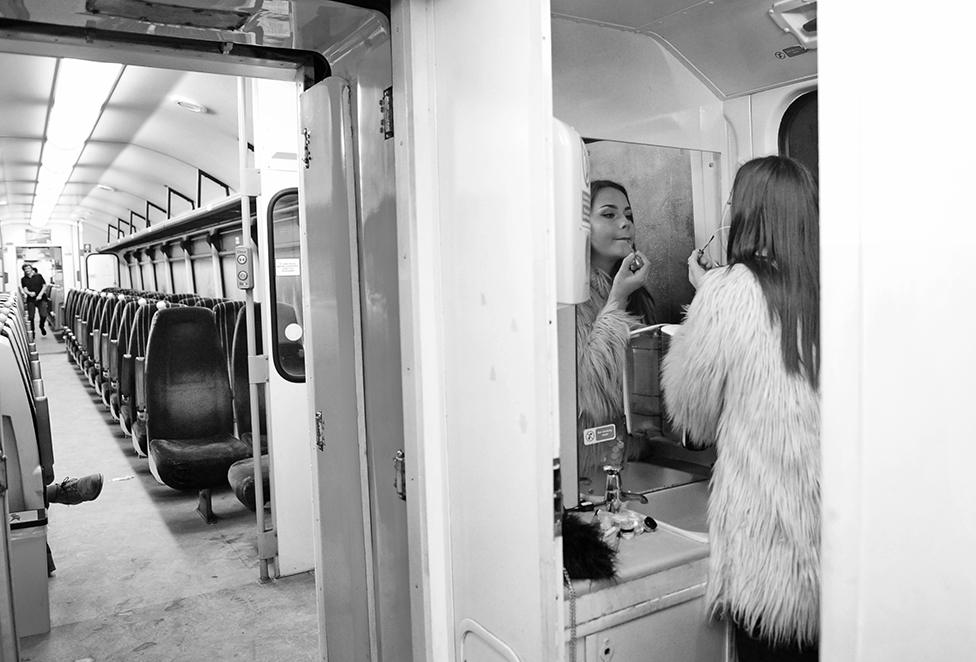 A woman puts on her lipstick in a train toilet