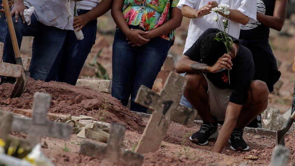 Relatives of a victim of the novel coronavirus disease Covid-19 mourn as their loved one is buried