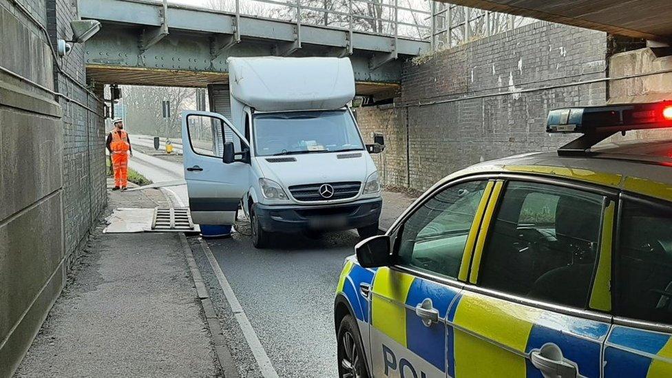 Van stuck under bridge