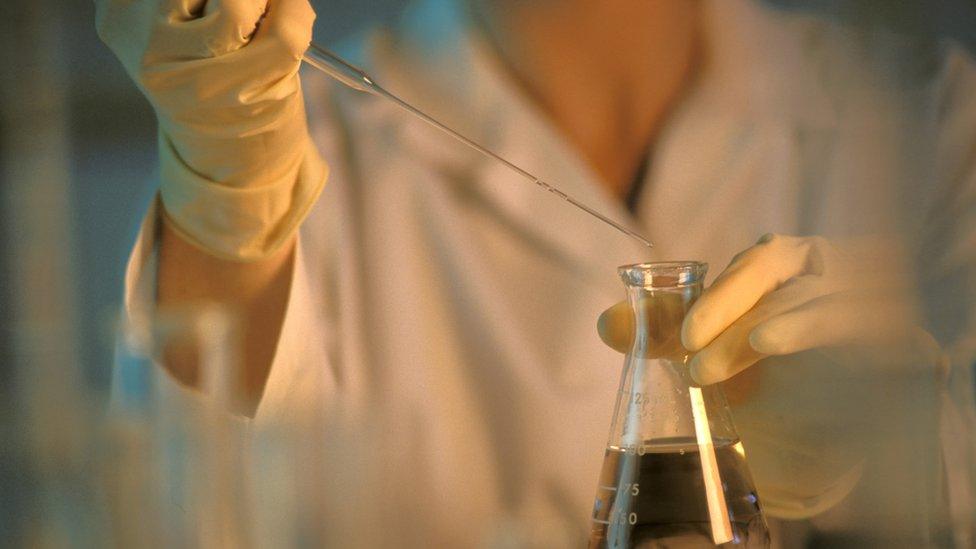 A woman holding chemistry equipment