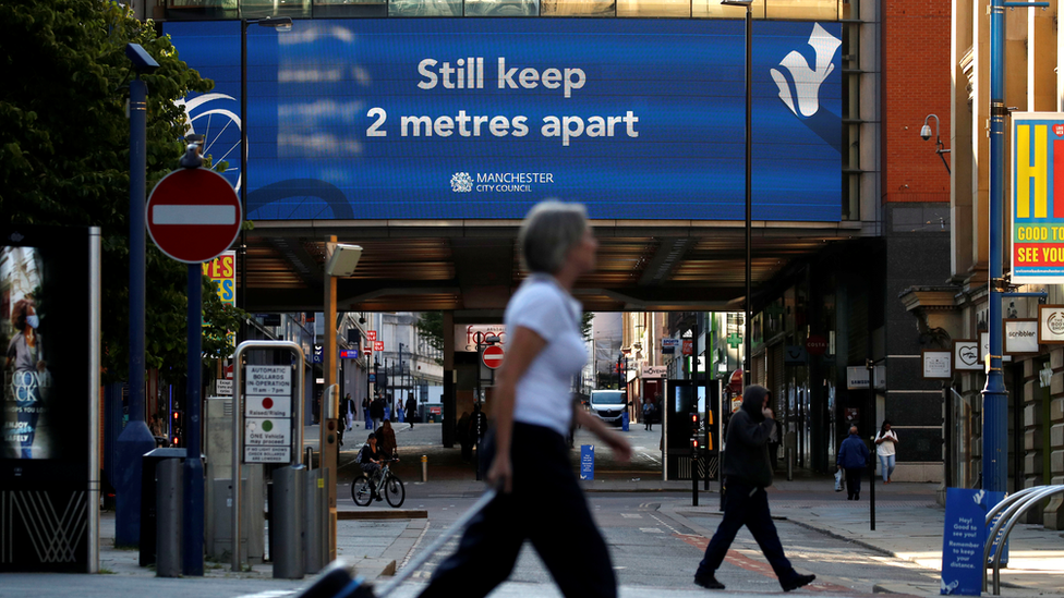 Woman walks past social distancing billboard