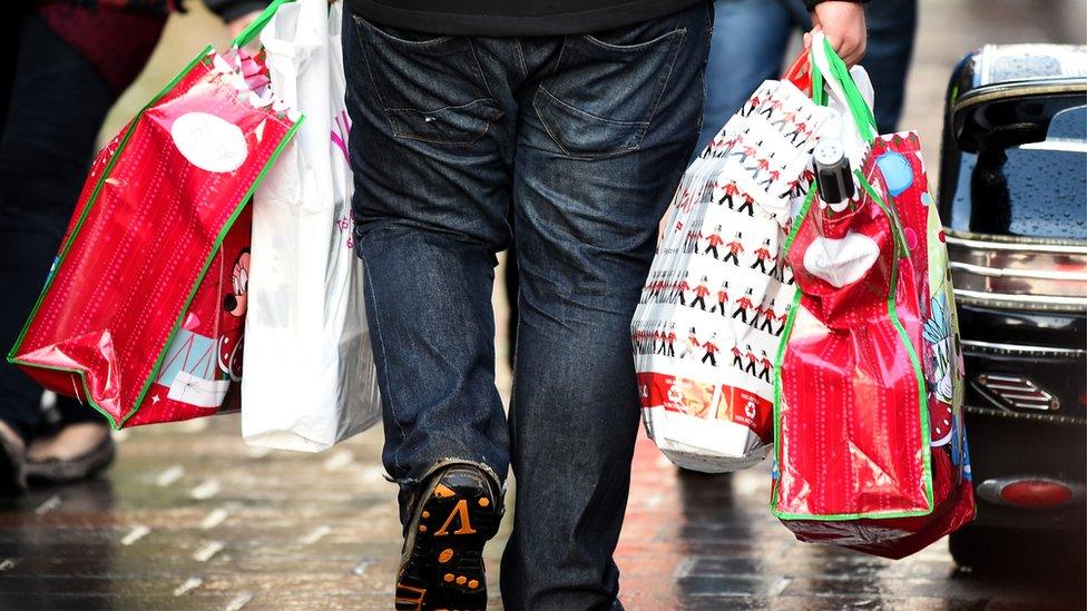 A man is seen carrying multiple bags of Christmas shopping