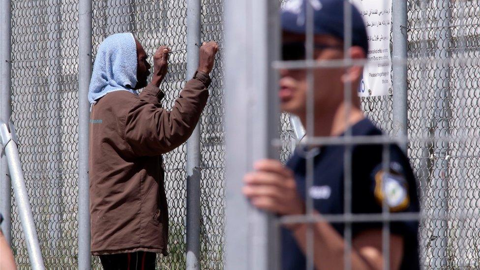 A man looks through a gate at the Moria refugee camp where asylum-seekers are held at the complex on April 15, 2016 in Mytilini on Lesbos