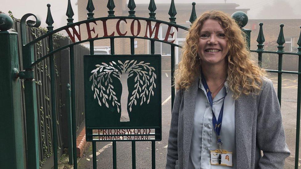 A woman with curly hair at a school gate