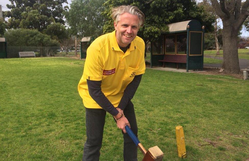 James Bartlett stands on a trugo field, holding a mallet