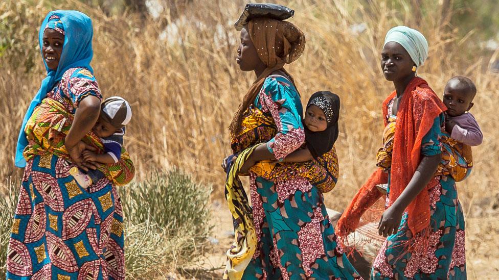 Women in Tamale in Ghana walking each with a baby on their back