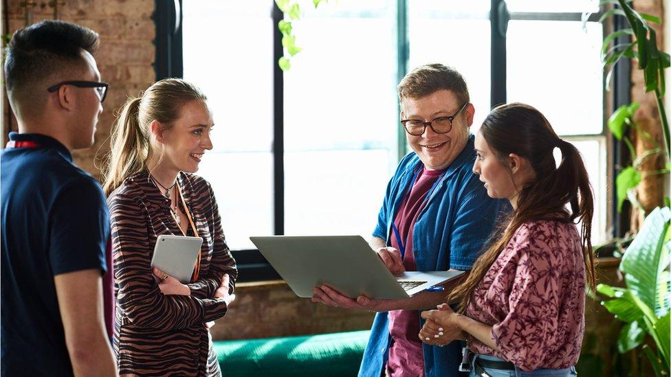 Young people talking around a laptop