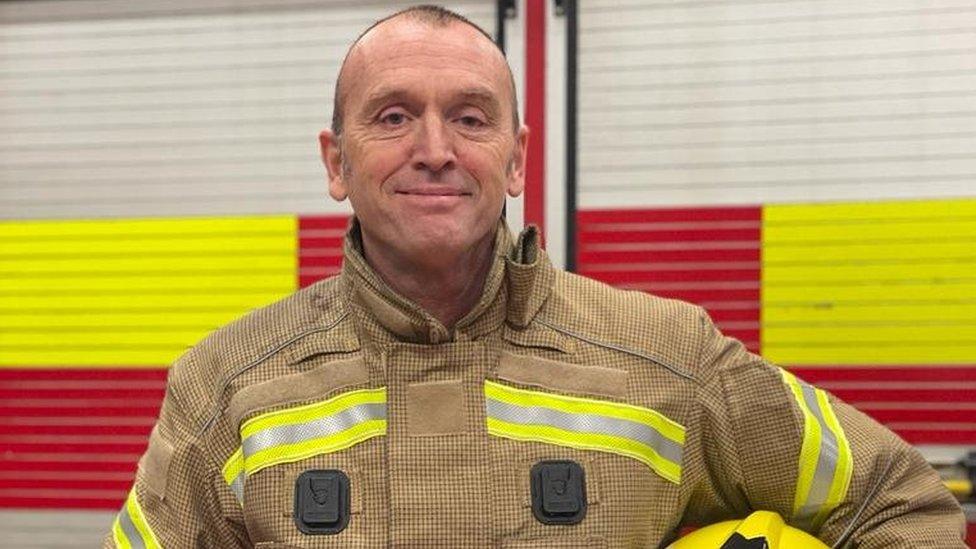 A man in fire uniform smiles at the camera