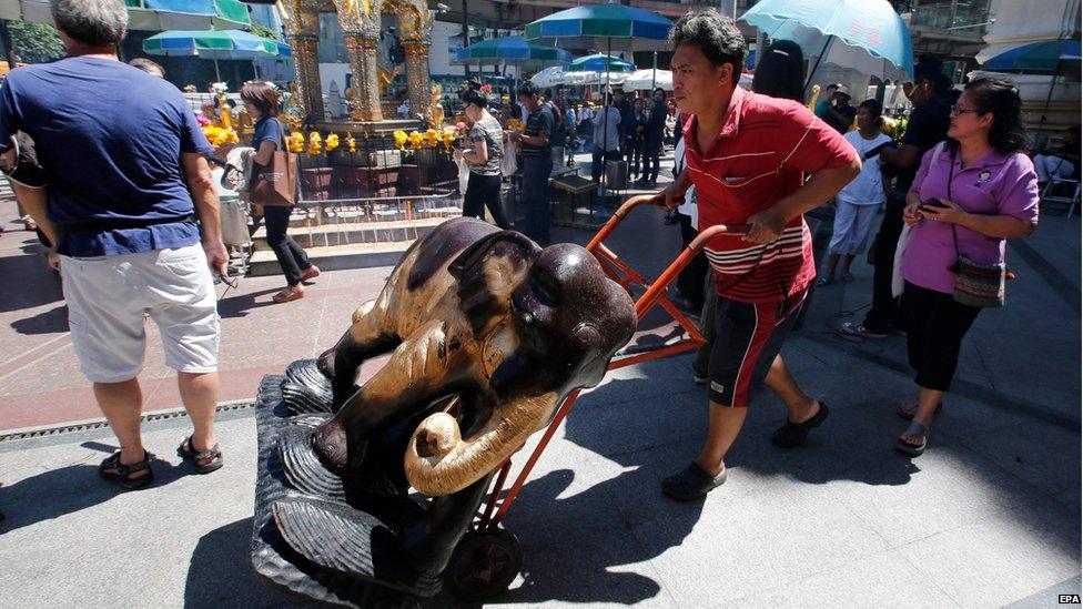 Shrine workers move elephant statues as tourists return