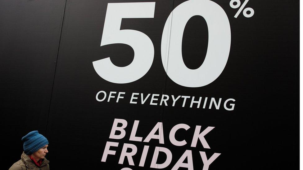 A woman walks past a Black Friday sale sign on Oxford Street on November 24, 2017 in London, England