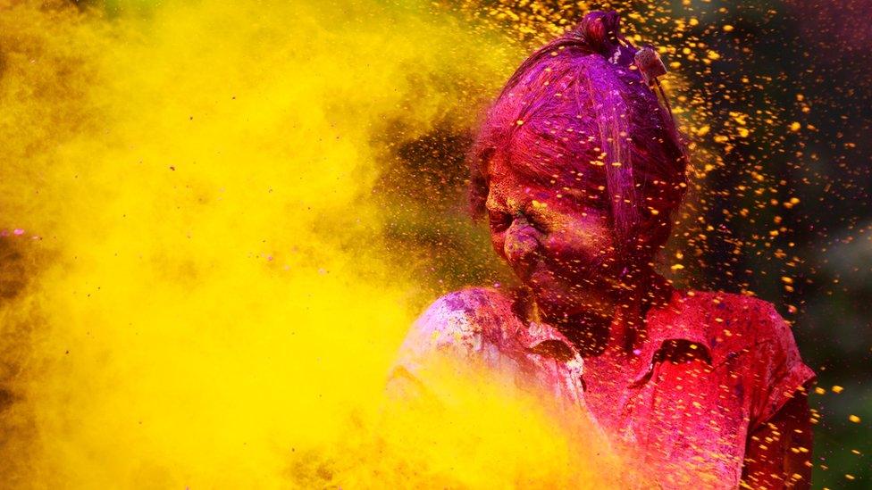 A girl covered in coloured powder closes her eyes