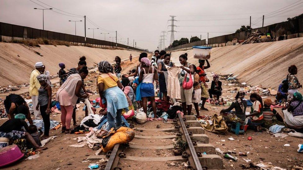 Hawkers sell their products in an improvised market across a train track in the Viana district in Luanda