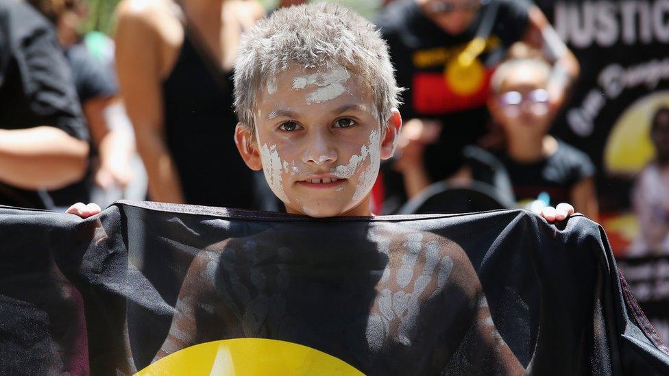 A young boy holds up an Aborginal Flag in Sydney