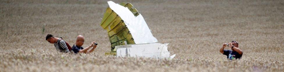 Malaysian air crash investigators take photos of the crash site of Malaysia Airlines Flight MH17, near the village of Hrabove (Grabovo), Donetsk region 22 July 2014.