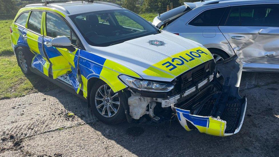 Police cars damaged after being rammed by tractor