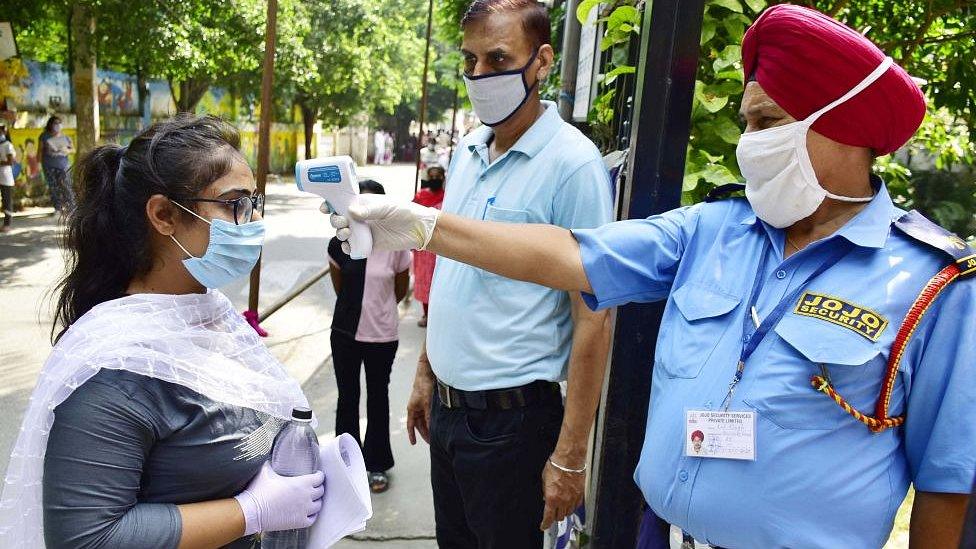 A temperature check is carried out on a student waiting to enter an exam centre on September 13, 2020 in Amritsar, India.