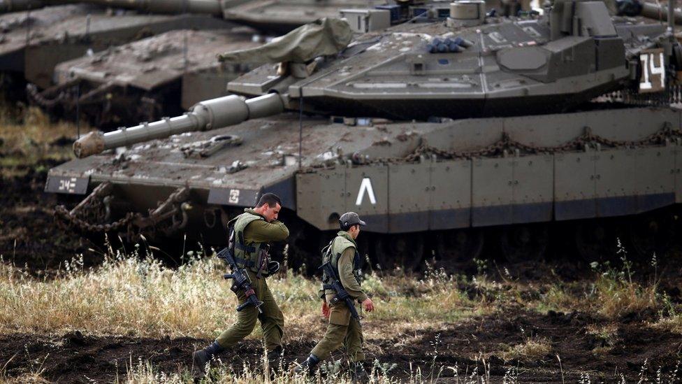 Israeli soldiers walk next to tanks near the Israeli side of the border with Syria in the Israeli-occupied Golan Heights, Israel May 9, 2018