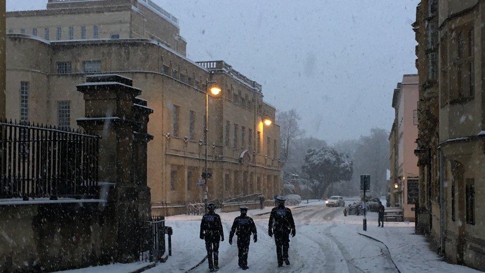 Three police officers walking through the snow in Oxford