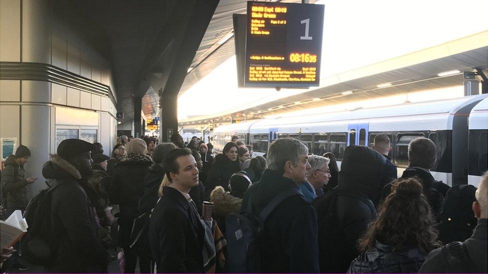 Commuters waiting for a train on a crowded platform