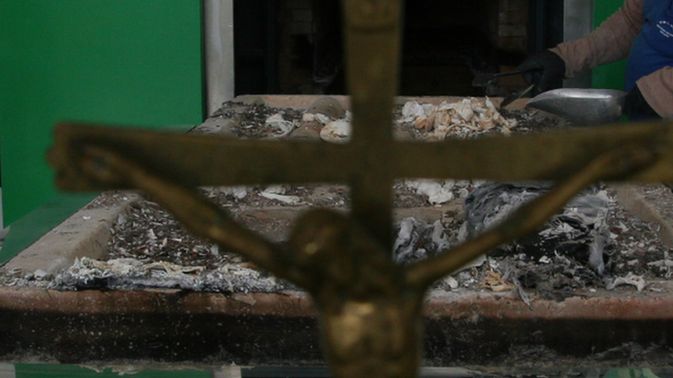 A worker collects ashes after cremation. File photo