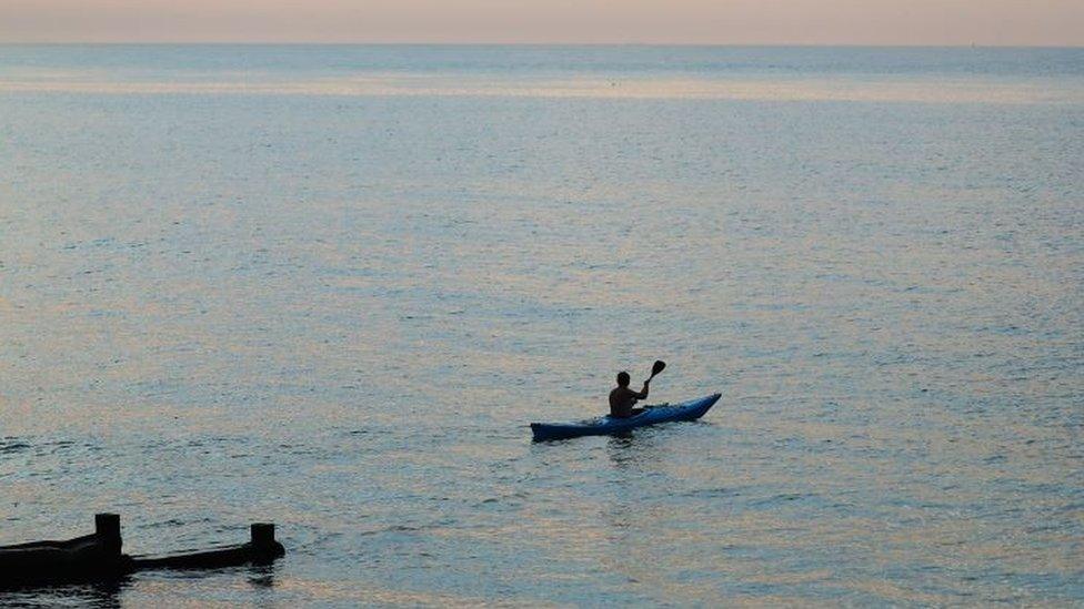 A man kayaks in the sea