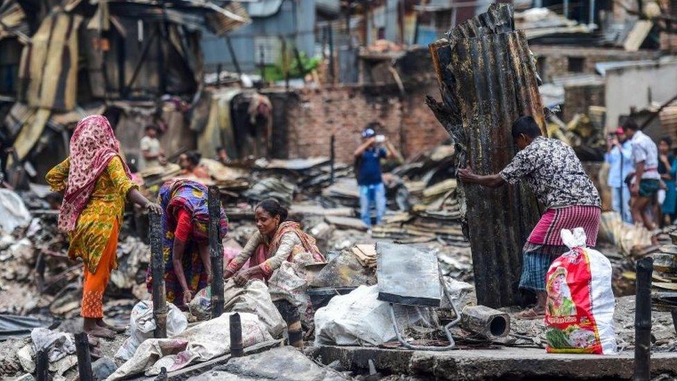 Residents search for household belongings in a slum in Dhaka on 18 August 2019,