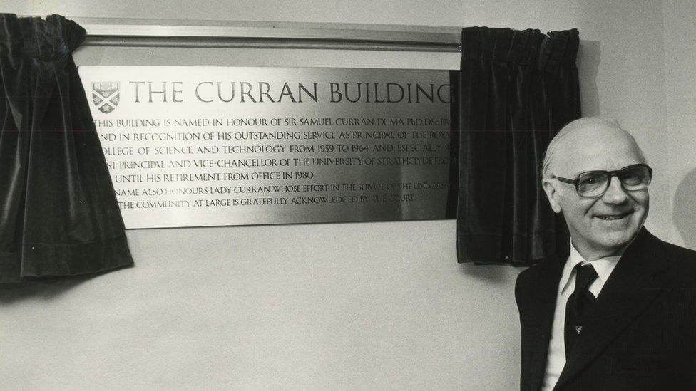 Sir Samuel Curran standing in front of the plaque at the building named in his honour