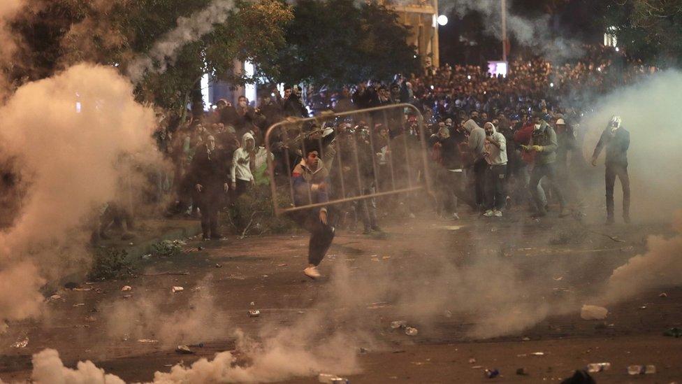 Demonstrators move metal barriers while engulfed in tear gas during clashes with security forces in Beirut