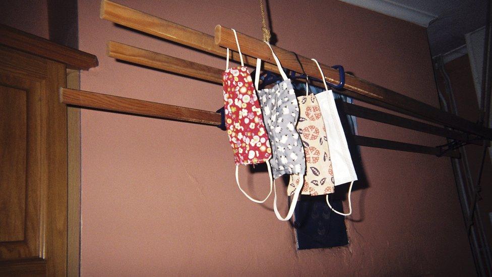 Three colourful face masks hang from an airing rack